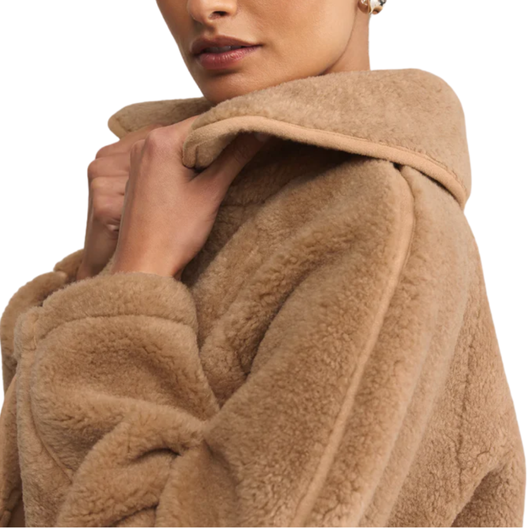 Close-up of a person wearing a beige fleece coat on a white background