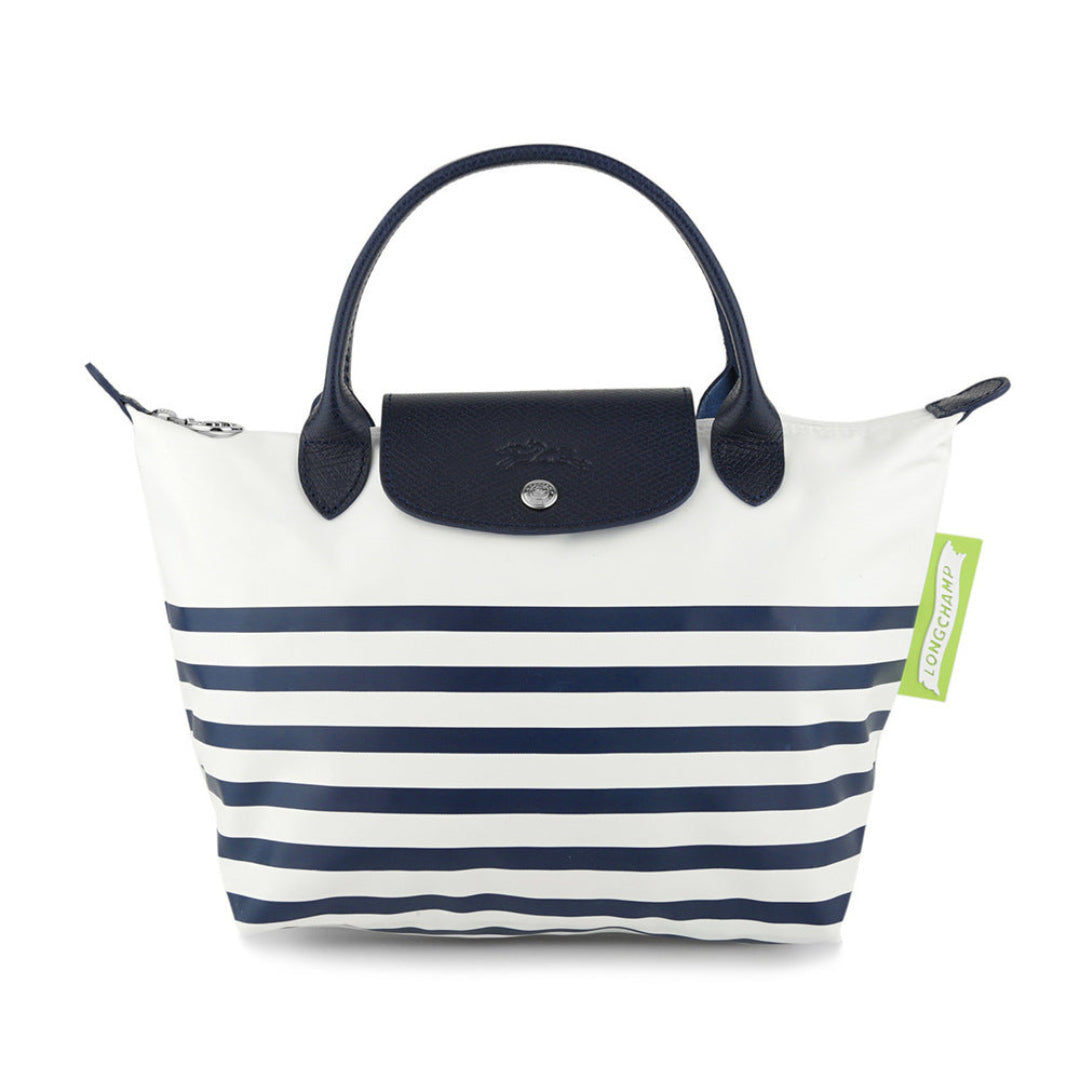 A Le Pliage tote bag by Longchamp featuring navy blue horizontal stripes on a white body, with a navy blue leather top handle and flap closure.